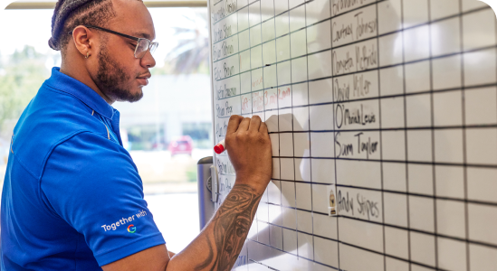 A male ADT corporate intern writes on a white board.