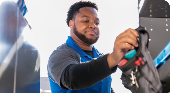 A male ADT Field Operations employee hangs up his tool belt, which is filled with tools.