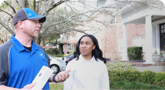 A male ADT Field Operations employee talks with a female homeowner outside her home.