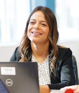 A female ADT employee sitting behind her computer and talking with a colleague.