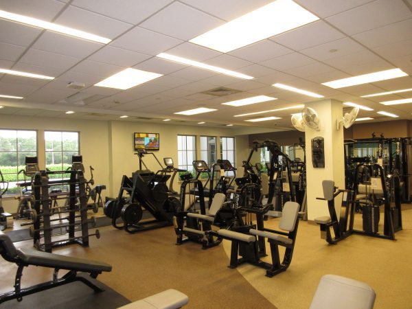 room with multiple exercise machines in a row and windows