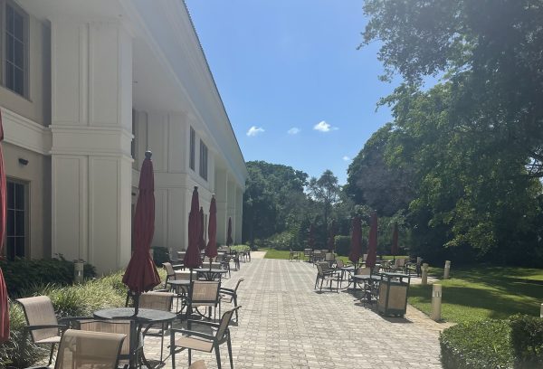 umbrella tables on a long walkway with trees lining it