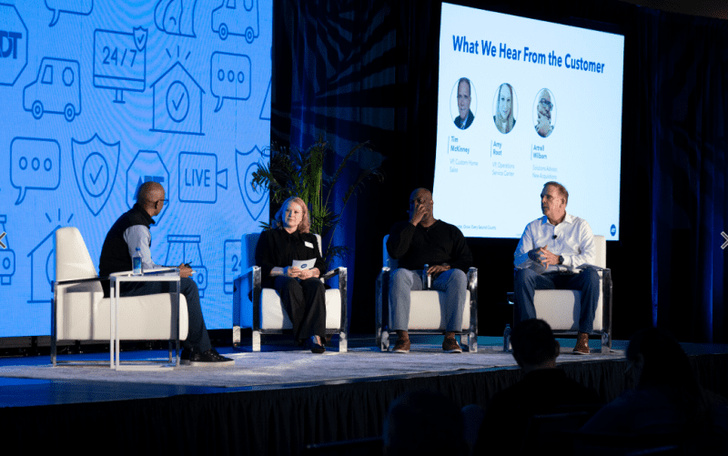 4 people sitting in chairs on a stage facing each other speaking