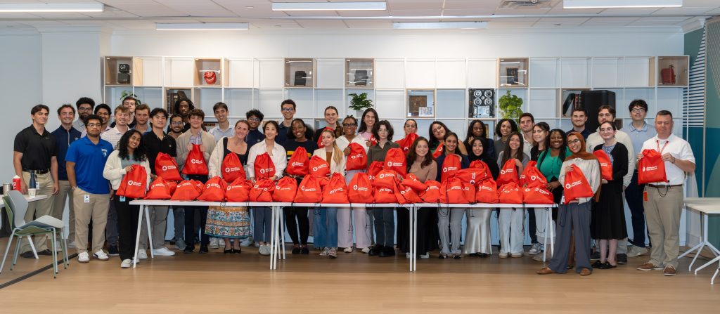 large group of people holding red American Red Cross bags
