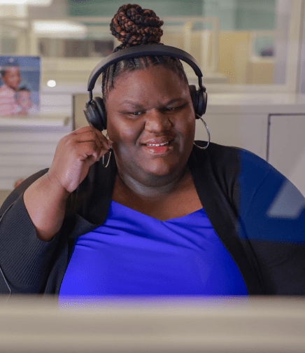 A female ADT Customer Care employee wearing a headset and touching the microphone on headset.